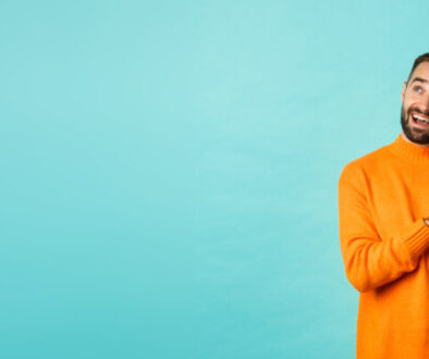 Handsome man thinking and using digital tablet, shopping online and pondering ideas, looking at upper left corner, standing over light blue background