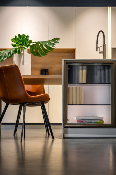 Modern kitchen interior with leather chair. Minimalist dining area with ribbed cabinet.