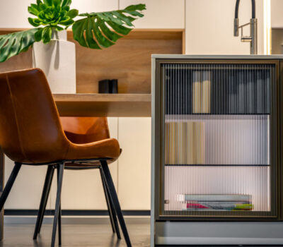 Modern kitchen interior with leather chair. Minimalist dining area with ribbed cabinet.